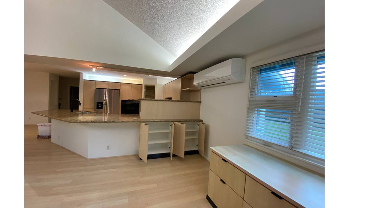A kitchen with a white countertop and wooden cabinets.